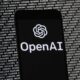 Openai Logo On Mobile With Binary Data Background